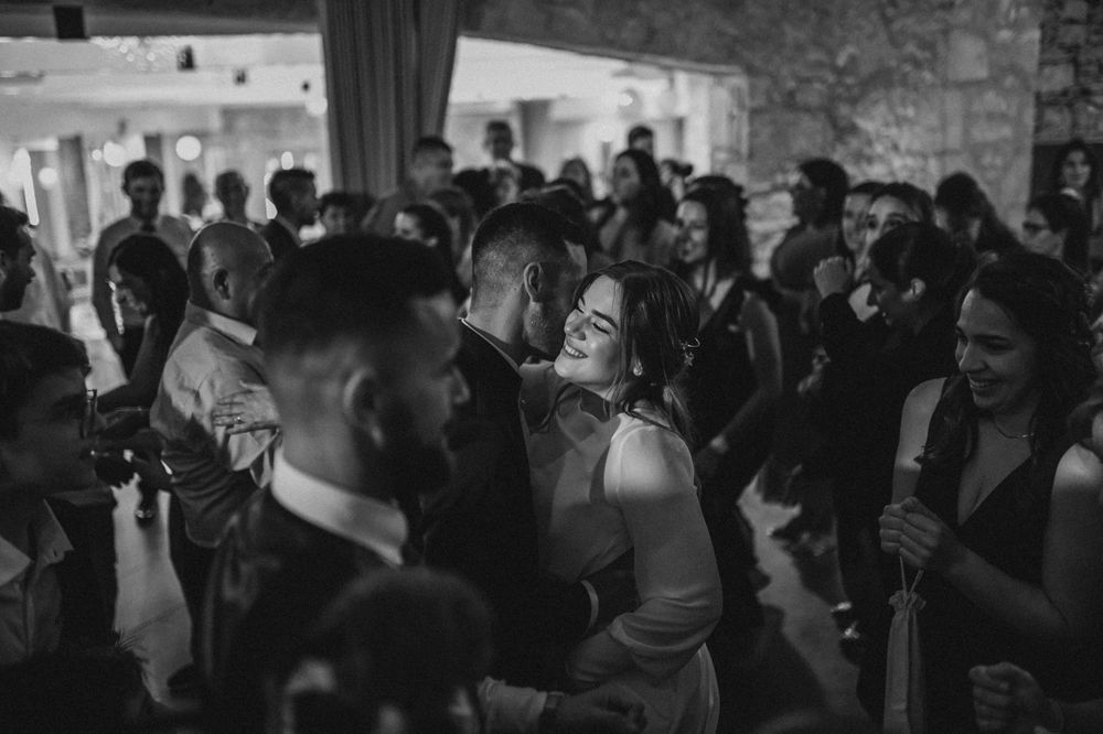 Black and white photo of crowded dance floor at a wedding reception.