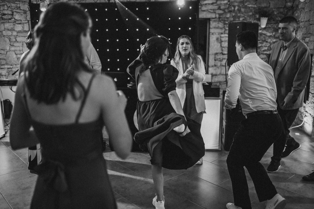 Partygoers dancing enthusiastically in a dimly lit stone venue with string lights.