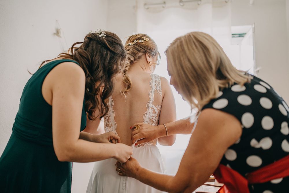 A wedding dress being adjusted and fitted in a bright room with polka dot details.
