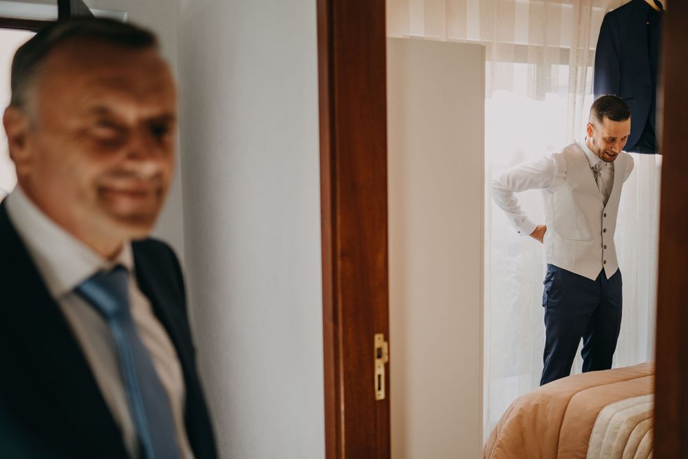 Getting ready scene with formal attire and suits visible in interior room setting.
