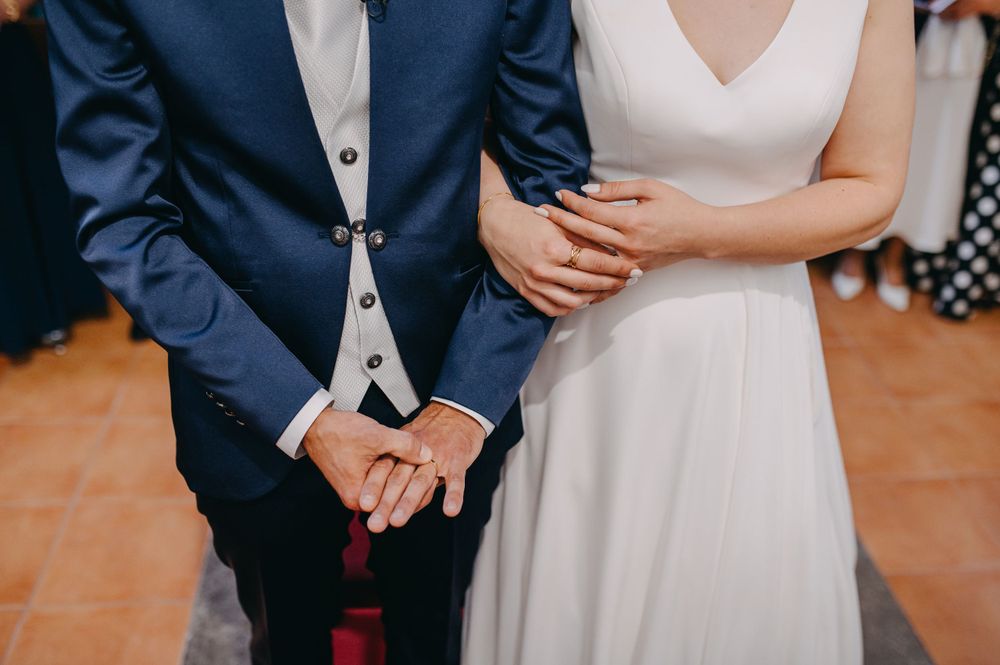 Close-up detail of a couple's hands during their wedding ceremony in formal attire.