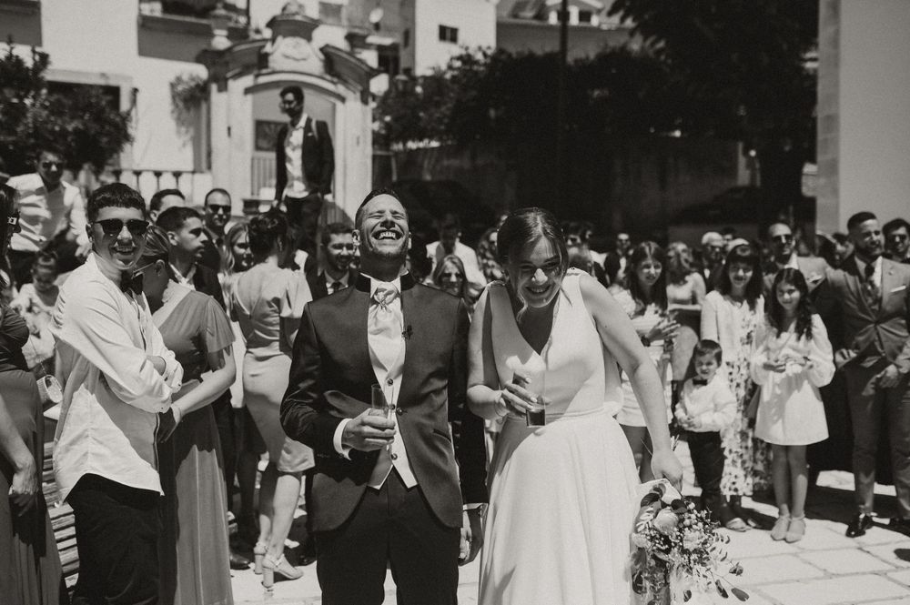 A black and white photo of newlyweds celebrating with guests outside.