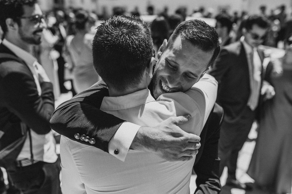 An emotional black and white moment showing two people embracing at a celebration.