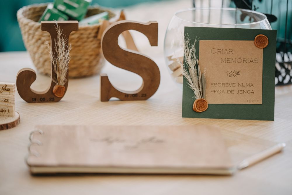 Wedding decor featuring wooden letters 'JS' and a green invitation card on a table.