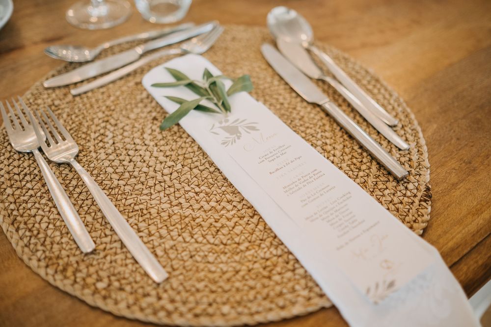 Wedding place setting with menu and floral sprig on woven placemat.