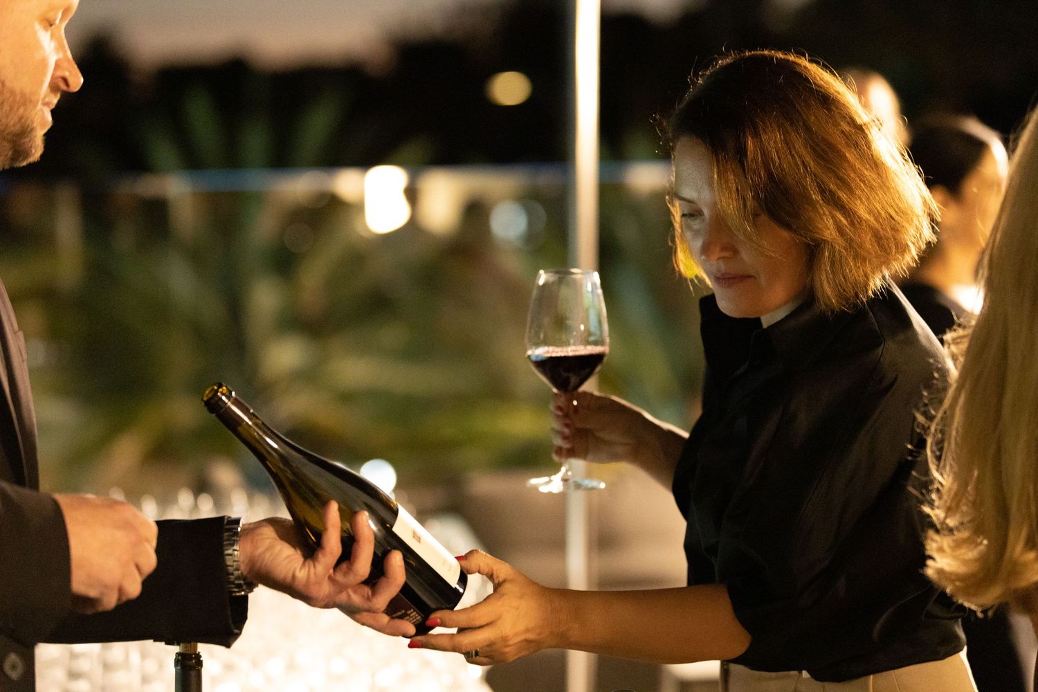 Candid photo of a women reading a wine label while at a corporate tasting event.