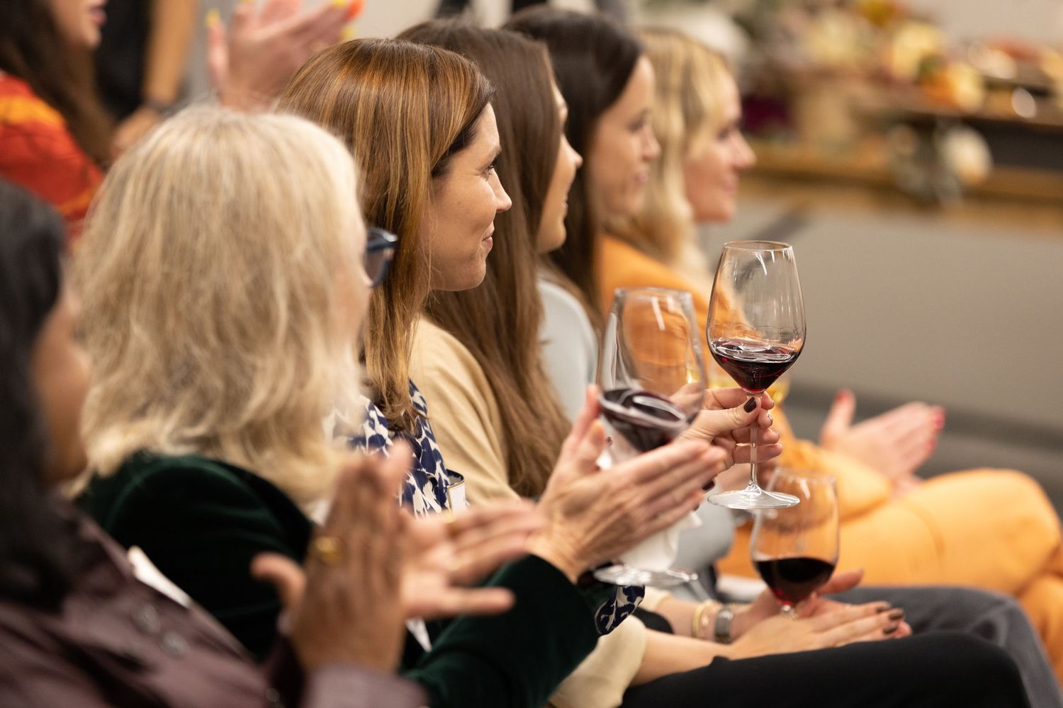 An audience of women applauding for a panel of speakers during a women in finance event.