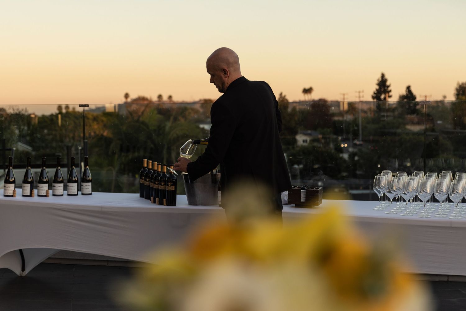 A bartender sets up an elegant display of wines for a tasting event at sunset.