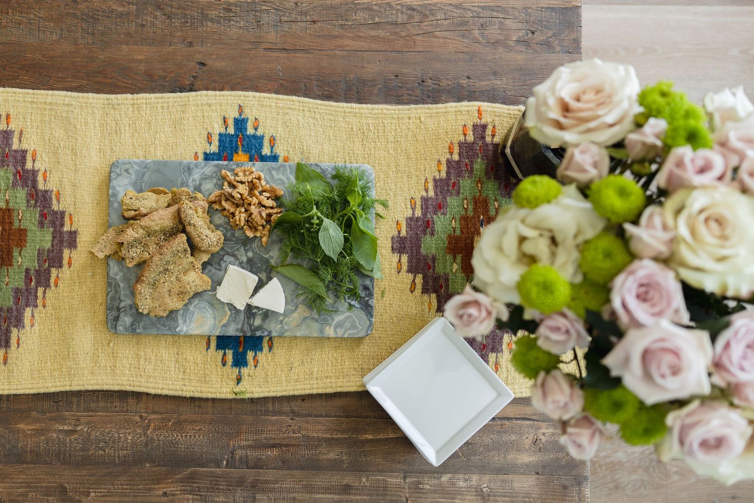 Image of a welcoming home environment featuring a coffee table covered in flowers and a elegant cheese board.