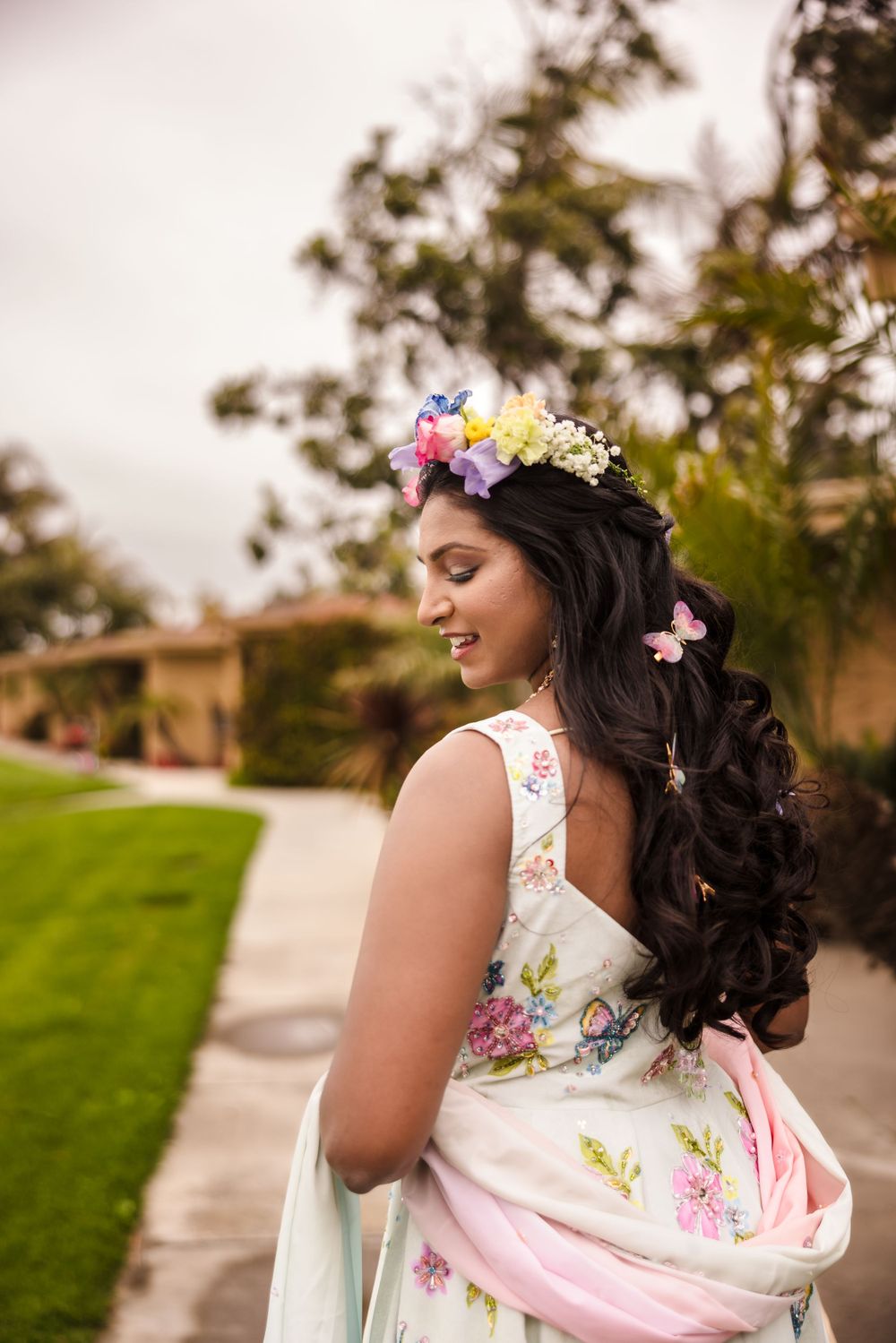 A floral-adorned bridal look featuring long dark curls and a colorful flower crown.