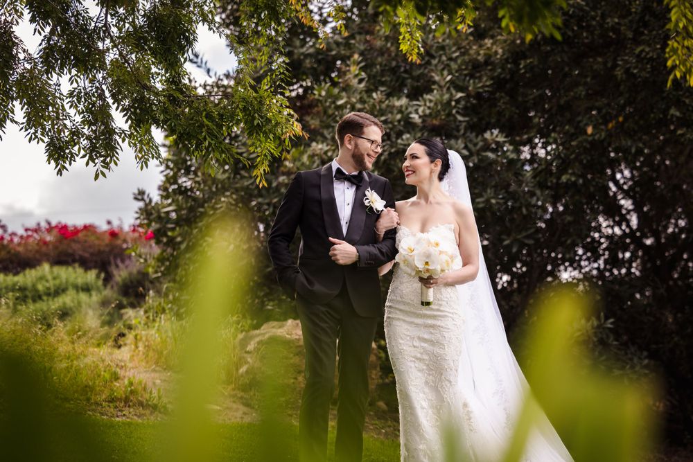 Elegant wedding photo amid beautiful landscaping and blooming flowers.