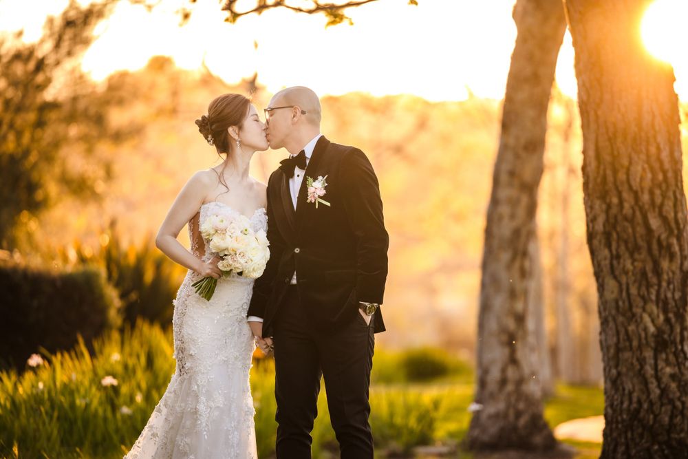 A romantic sunset wedding portrait with golden backlighting and natural landscape.
