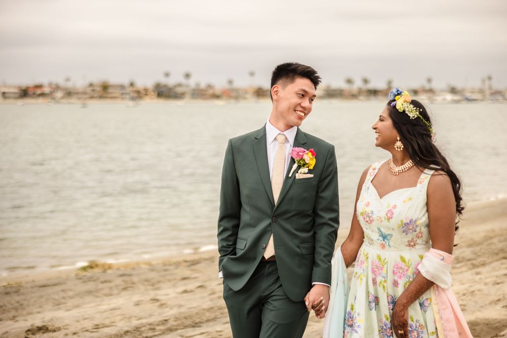 A couple shares a joyful moment on a beach with palm trees in the background.