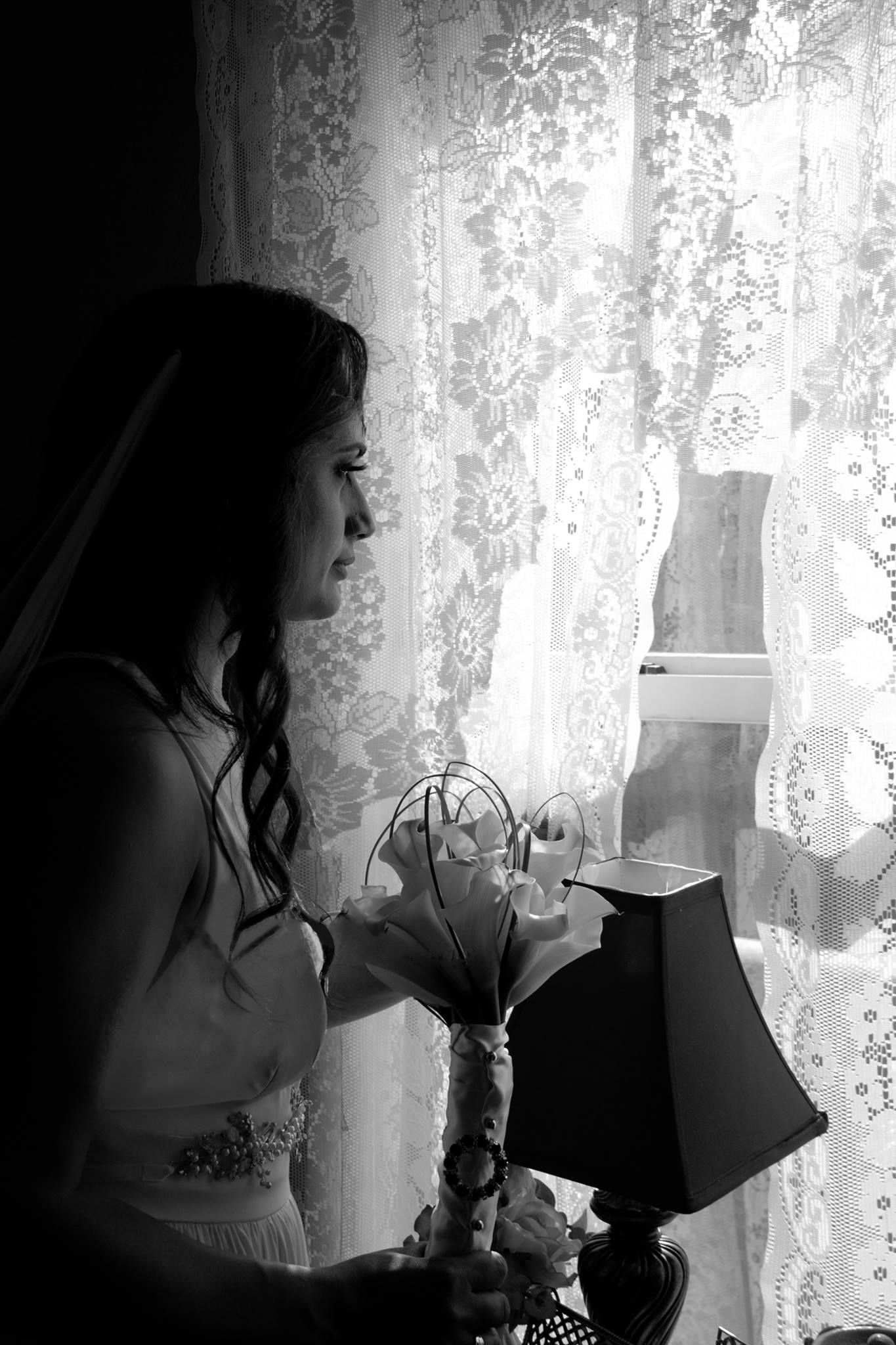 A silhouette of someone holding a bouquet near a lace curtained window.
Wedding photography