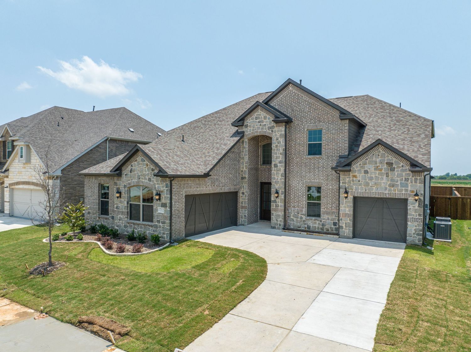 Street view of modern residential homes with stone facades and concrete driveways.