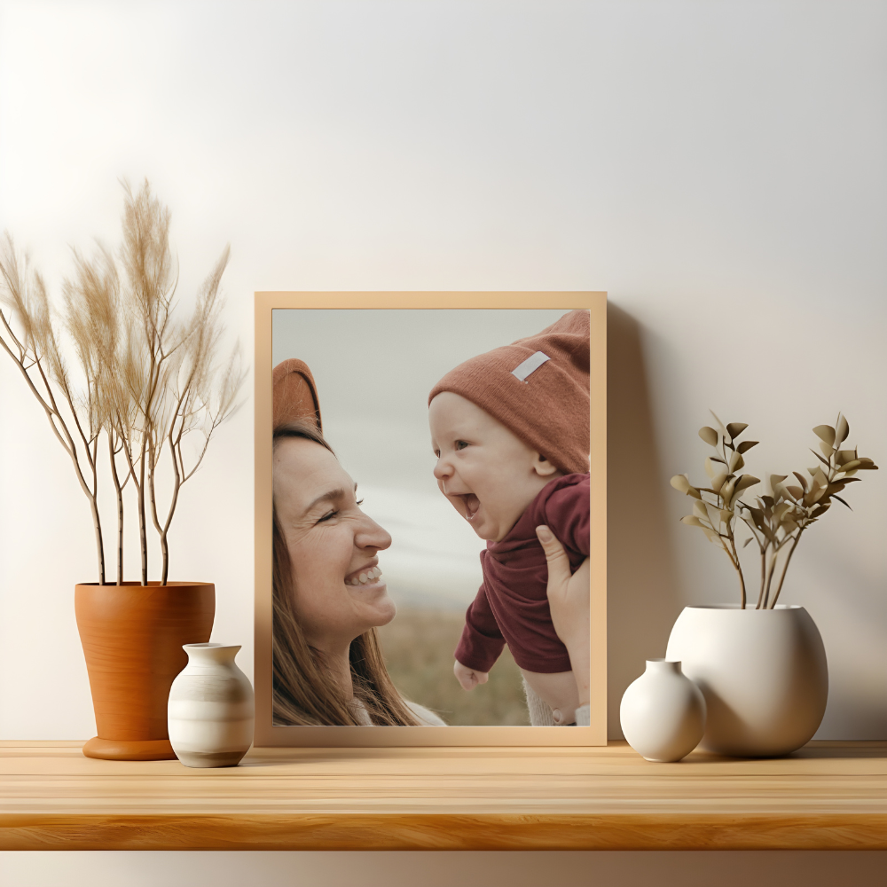 framed photo of mother holding smiling baby on a shelf with plants on either side