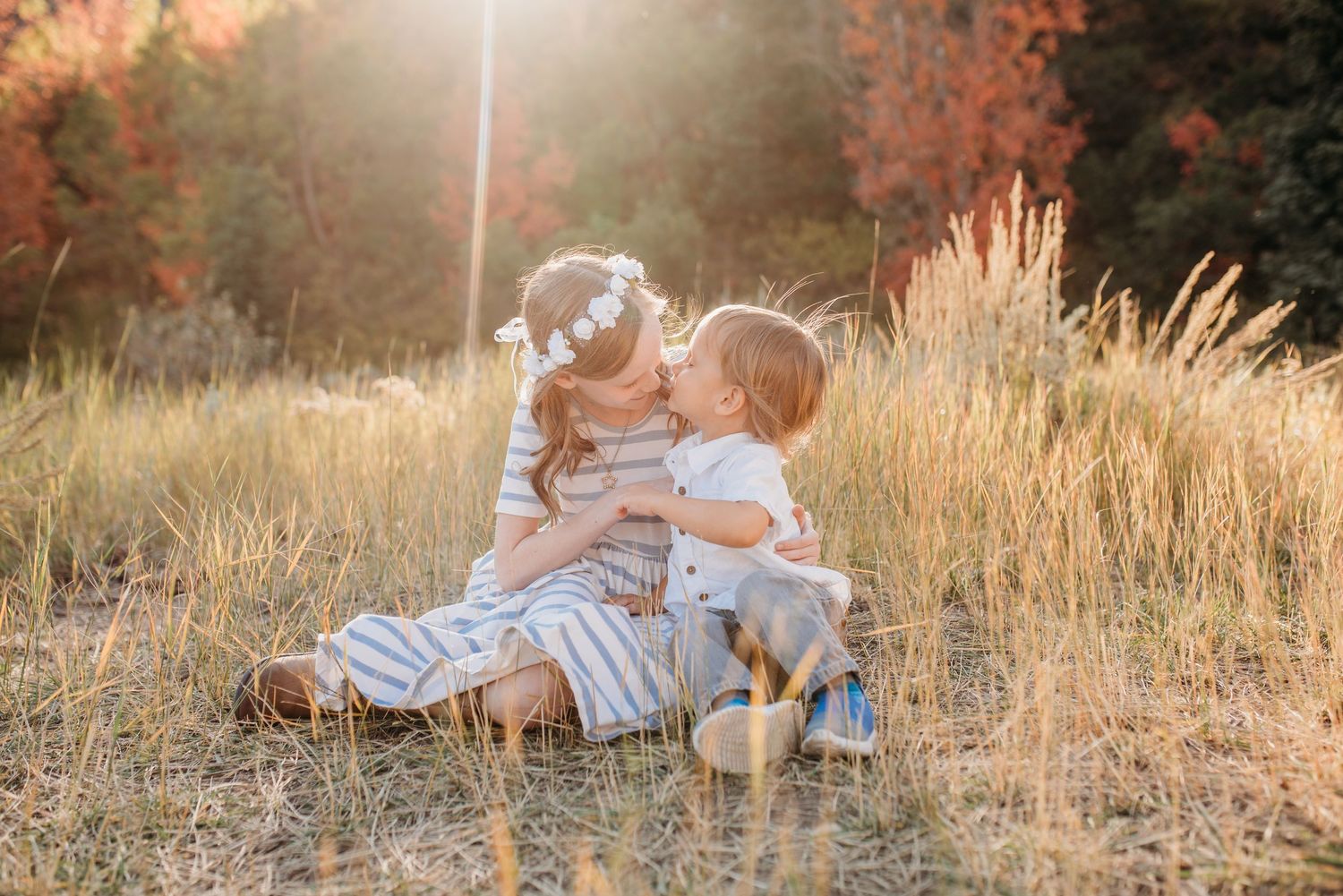 A tender moment captured in a golden field during sunset with warm autumn colors in the background.