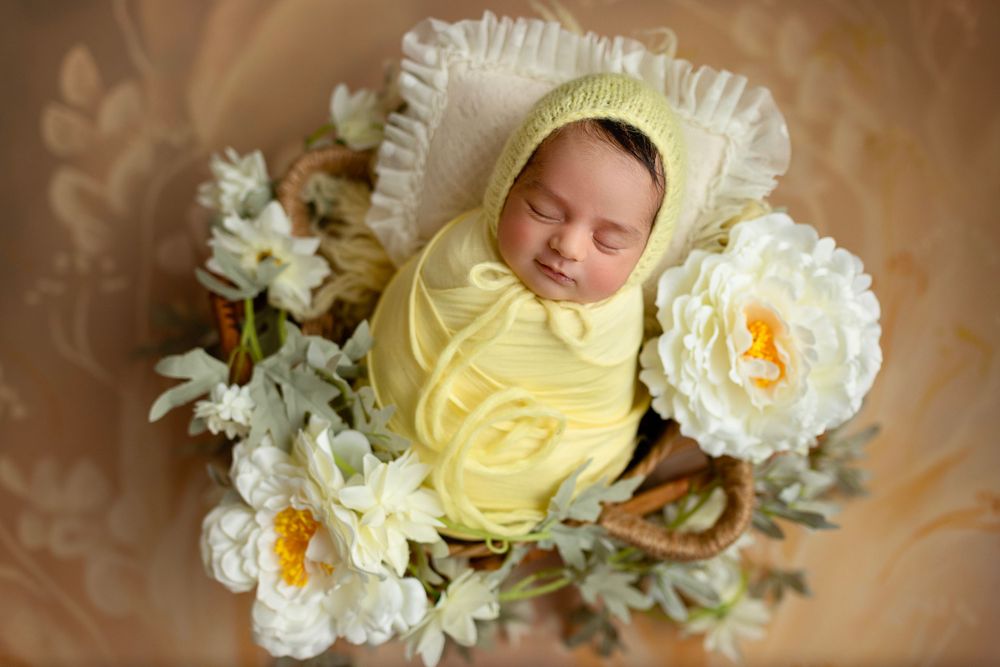 "Newborn baby peacefully sleeping on a soft, floral blanket in a cozy studio setup by a  photographer in Doha, Qatar