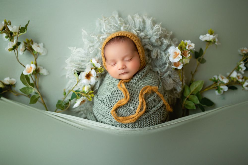 "Newborn baby peacefully sleeping on a soft, floral blanket in a cozy studio setup by a  photographer in Doha, Qatar