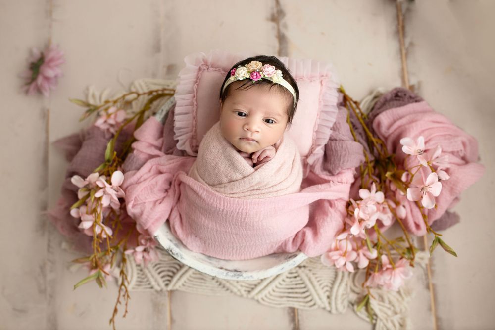 "Newborn baby peacefully sleeping on a soft, floral blanket in a cozy studio setup by a  photographer in Doha, Qatar