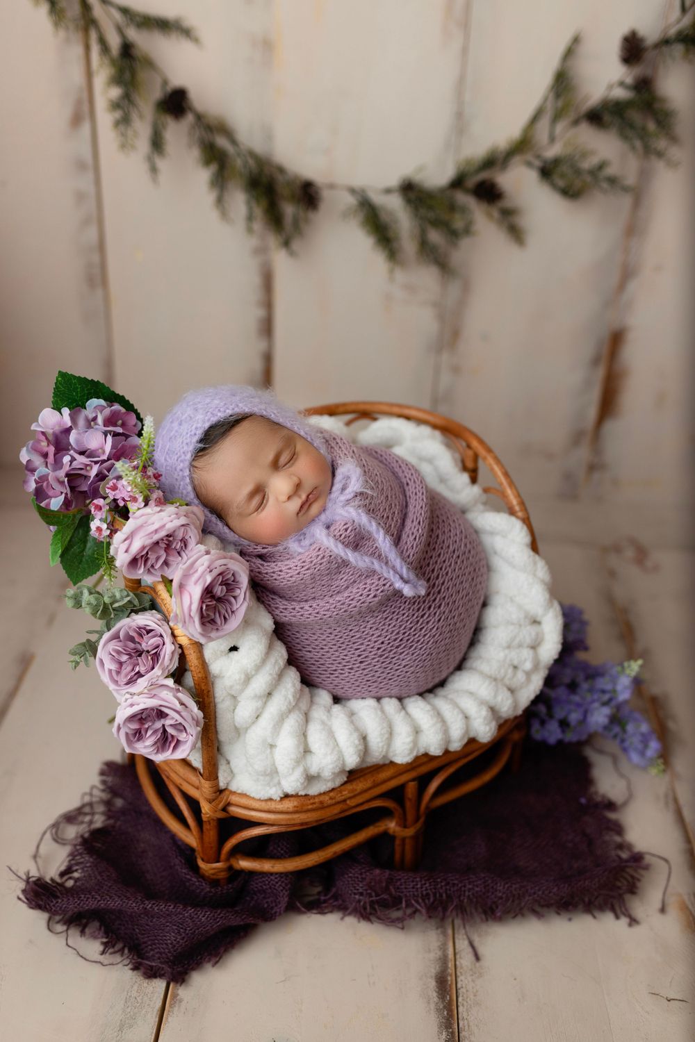 "Newborn baby peacefully sleeping on a soft, floral blanket in a cozy studio setup by a  photographer in Doha, Qatar