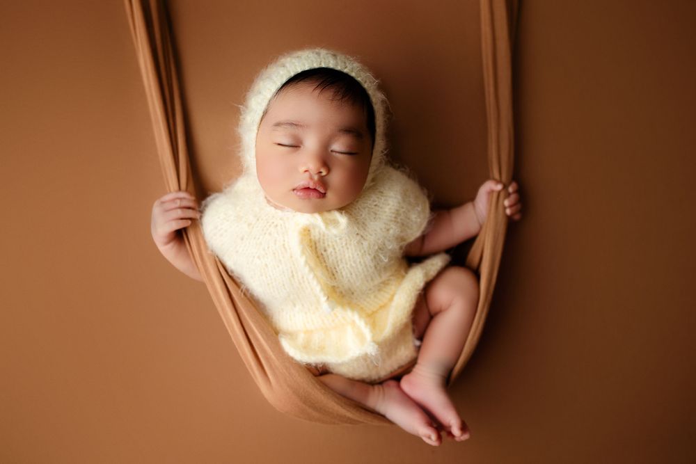 "Adorable newborn baby swaddled in prop peacefully sleeping. captured by a female photographer in Doha, qatar