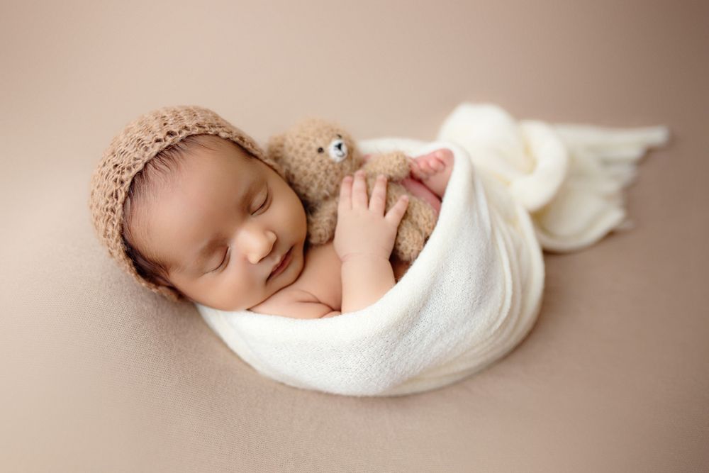 "Newborn baby peacefully sleeping on a soft, textured blanket in a cozy studio setup by a  photographer in Doha, Qatar