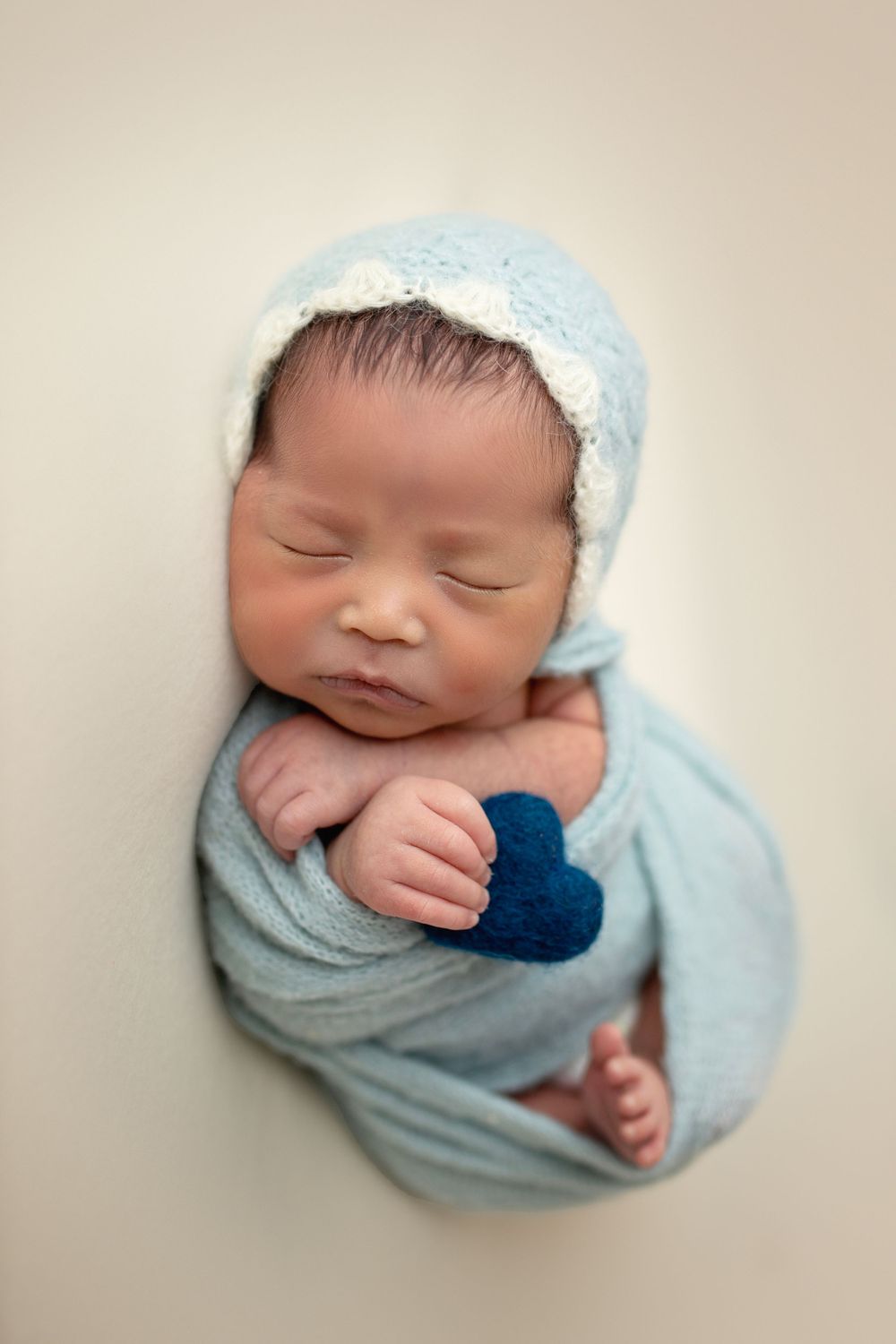 "Newborn baby peacefully sleeping on a soft, textured blanket in a cozy studio setup by a  photographer in Doha, Qatar