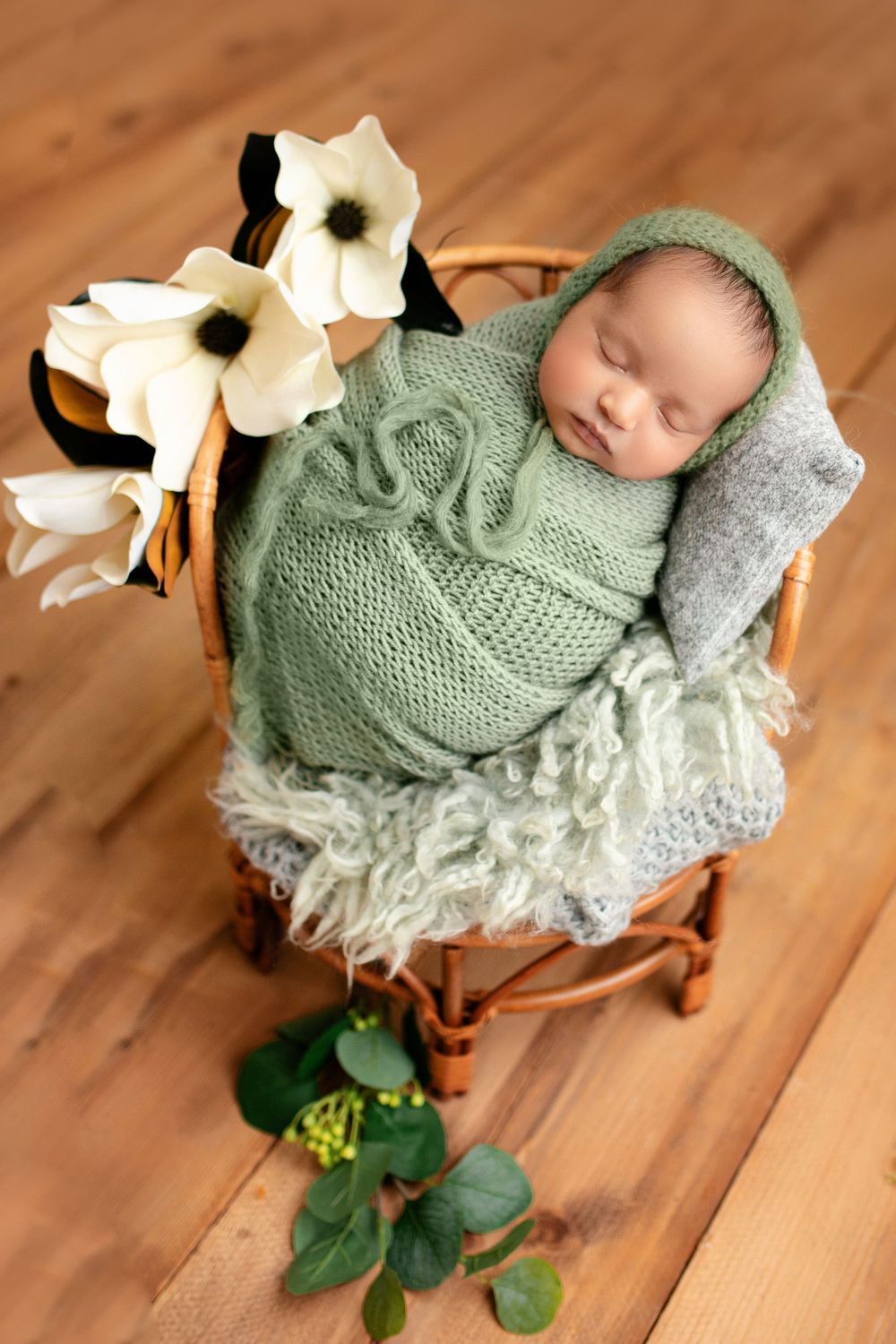 "Newborn baby peacefully sleeping on a soft, floral blanket in a cozy studio setup by a  photographer in Doha, Qatar