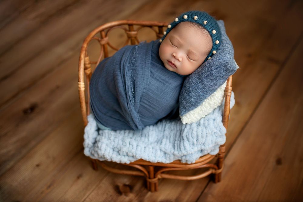 "Newborn baby peacefully sleeping on a soft, floral blanket in a cozy studio setup by a  photographer in Doha, Qatar