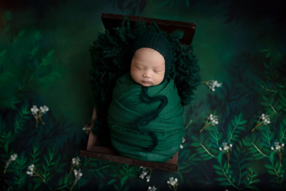 "Adorable newborn baby swaddled in prop peacefully sleeping. captured by a female photographer in Doha, qatar
