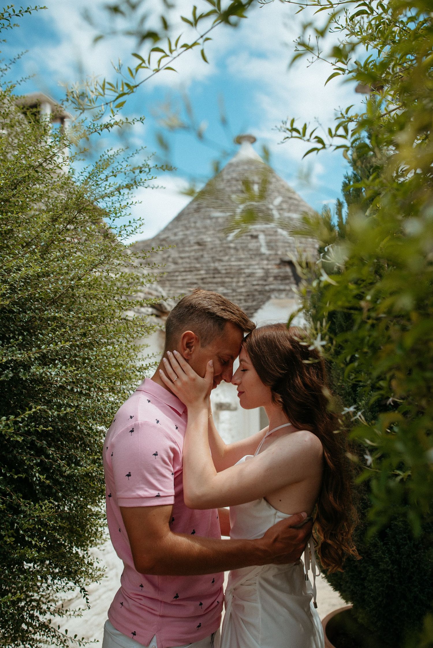 Romantic moment between couple in front of traditional stone trullo building.
