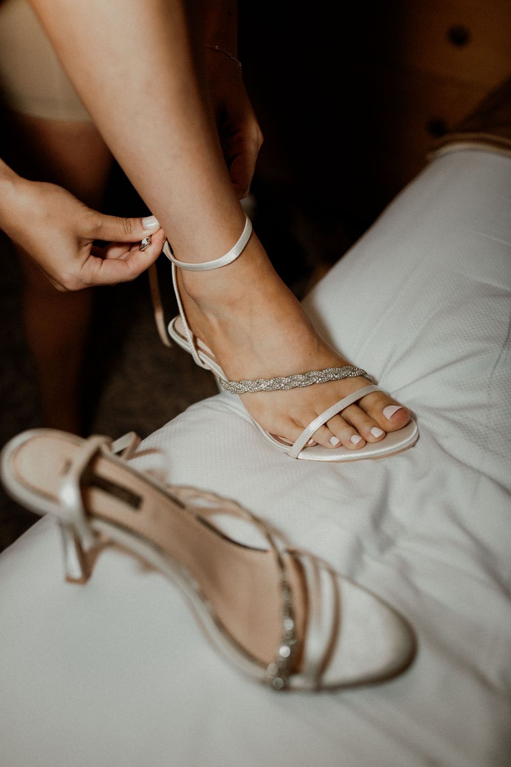 Close-up of sparkly bridal sandals being fastened on wedding day.