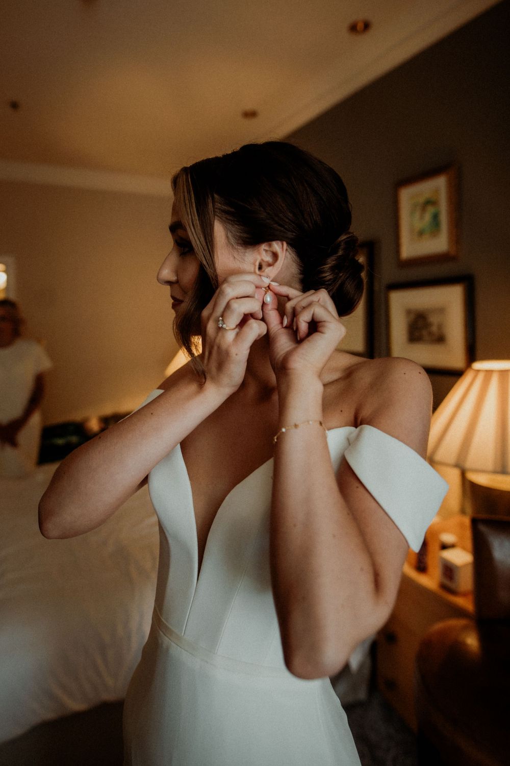 Elegant bridal preparation scene showing earring adjustment in warm lighting  London wedding photographer. The landmark