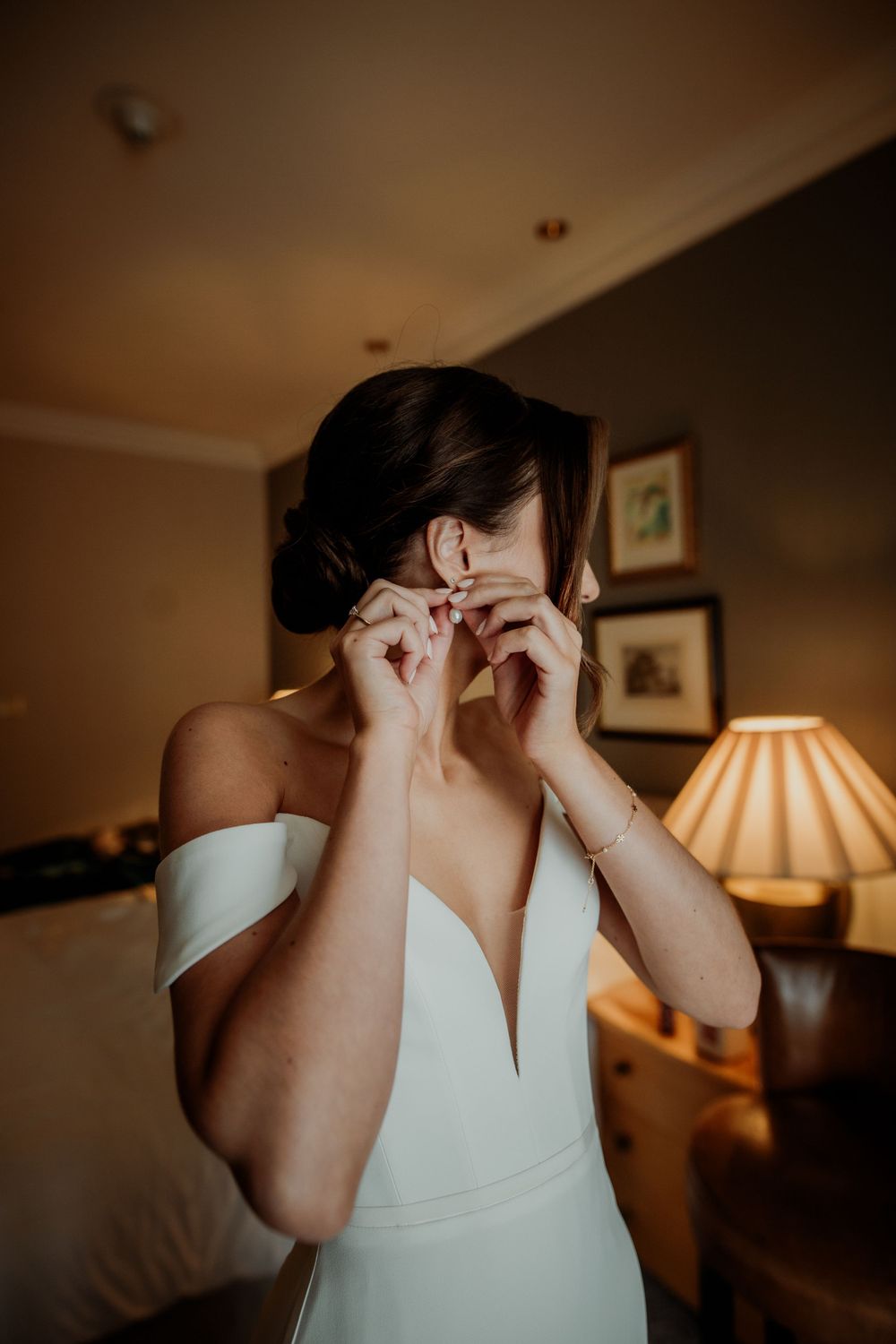 Getting ready scene showing final touches with jewelry in warm lighting.
