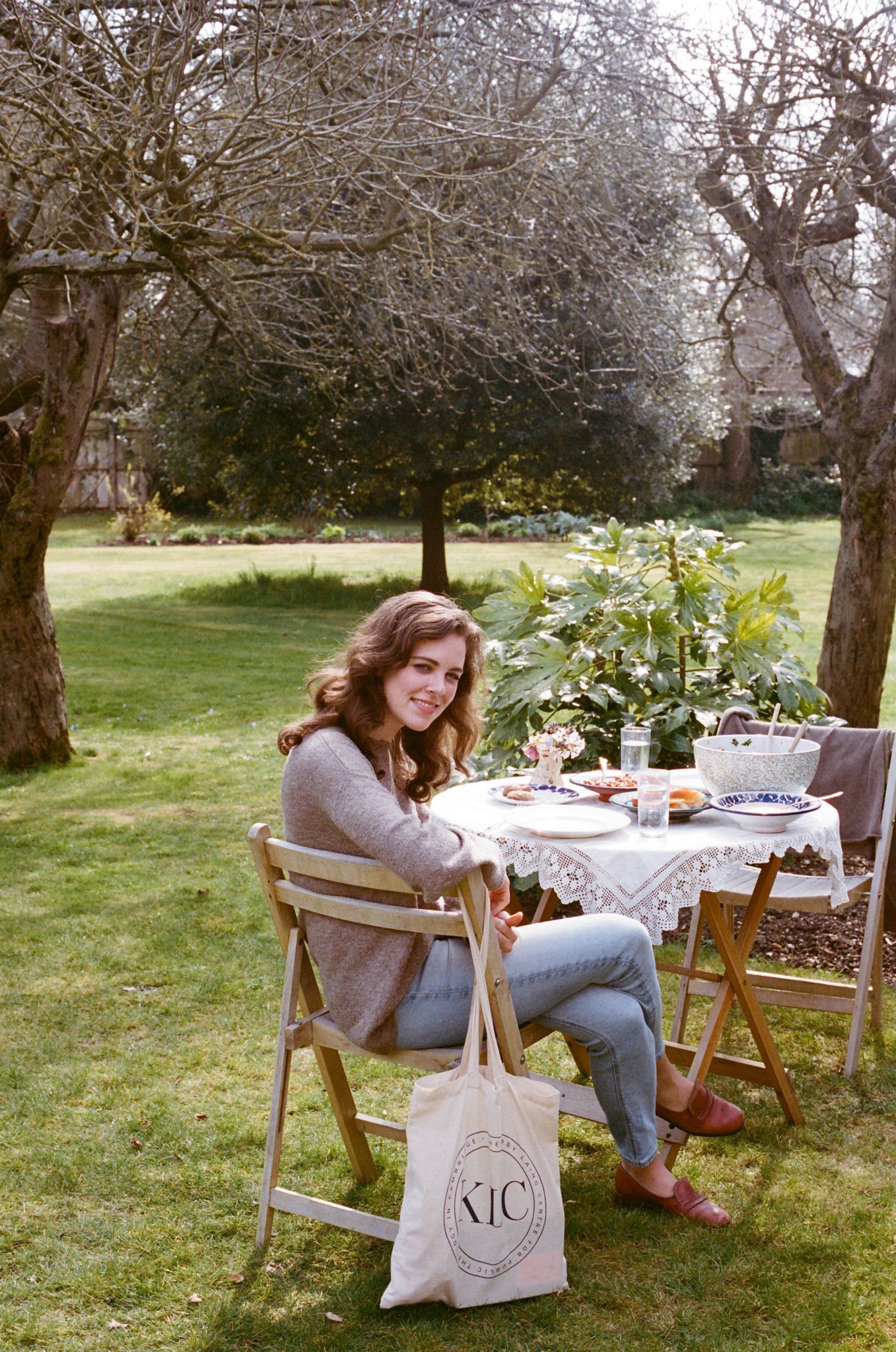 Outdoor garden scene with table setting and tote bag on a sunny day.