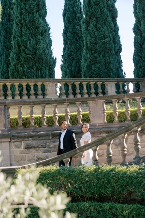 Elegant stone balustrade with tall cypress trees creates a romantic Italian garden atmosphere at a formal event.