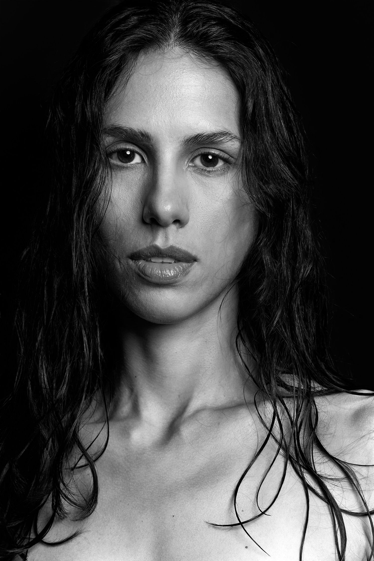 A dramatic black and white portrait series showing close-up artistic shots with windswept dark hair.