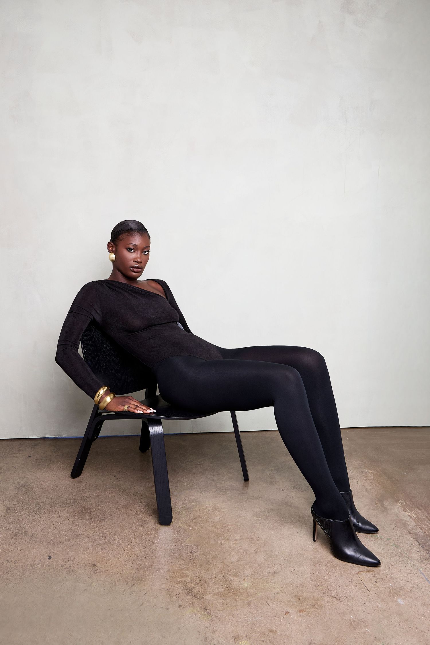 A sequence of fashion poses in black attire against a minimalist white studio backdrop.