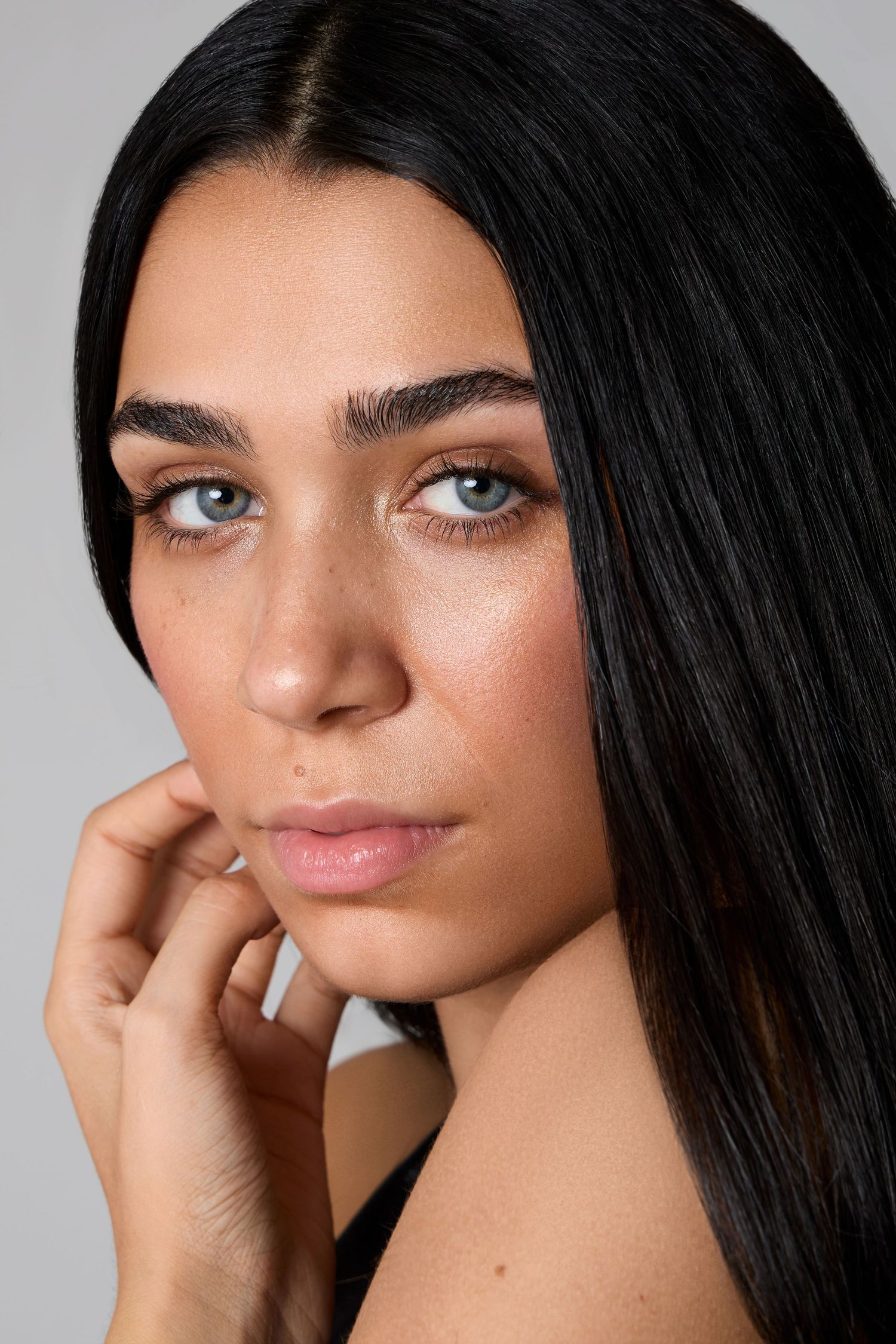 Four close-up beauty portraits showcasing glowing makeup and long dark hair against a neutral background.