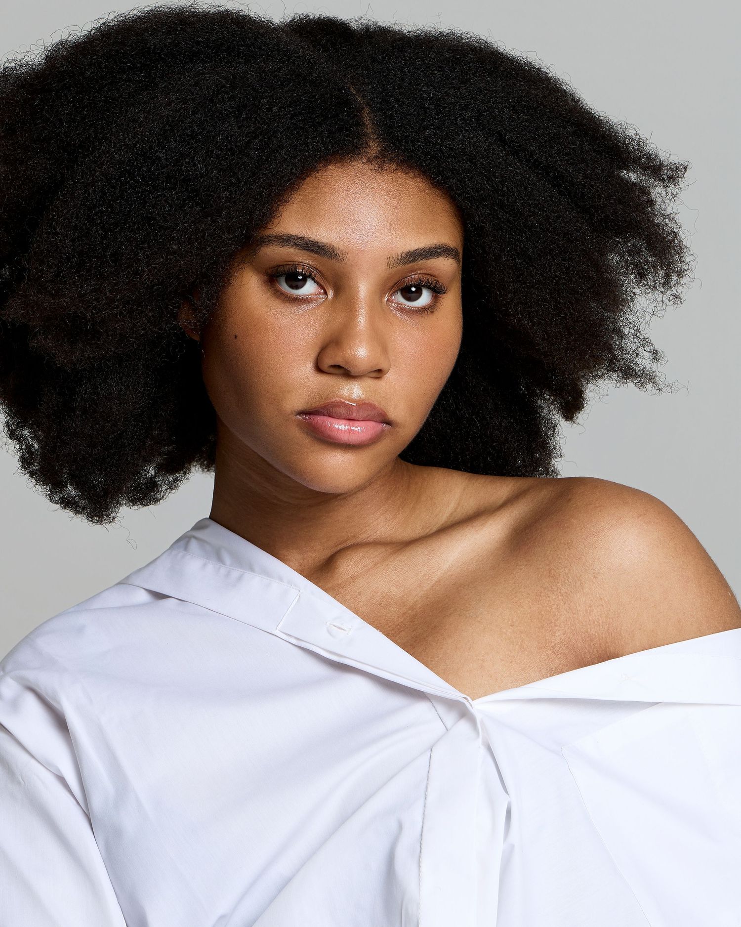 A sequence of close-up studio portraits showing natural curly hair and white shirt styling against a grey background.