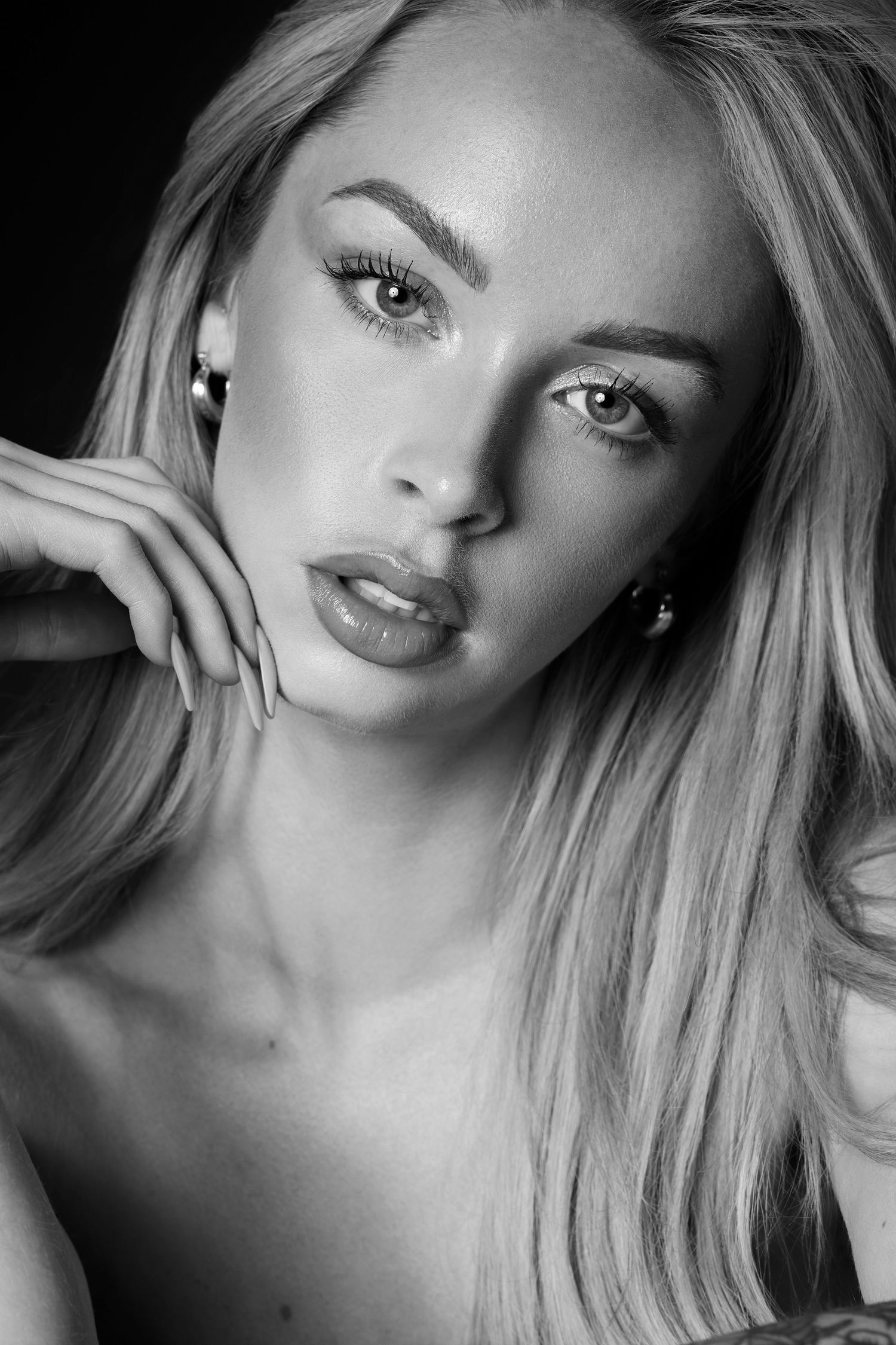 Black and white glamour portrait showing dramatic lighting on a blonde model with defined makeup.