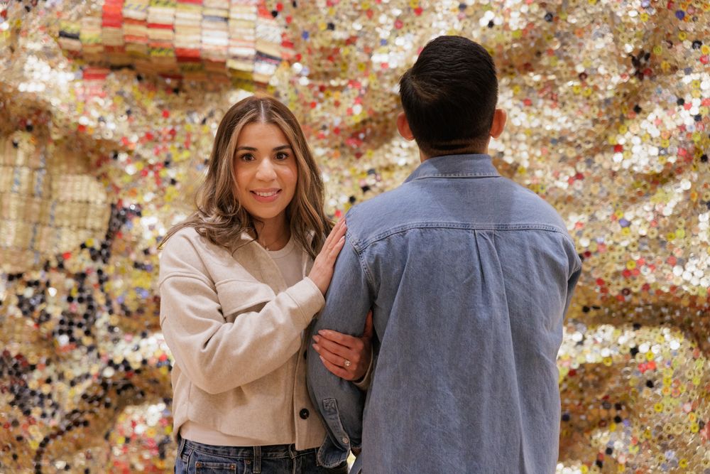 A couple standing in front of large gold sequins art piece at the Yale University Art Gallery. An engagement session at the museum.