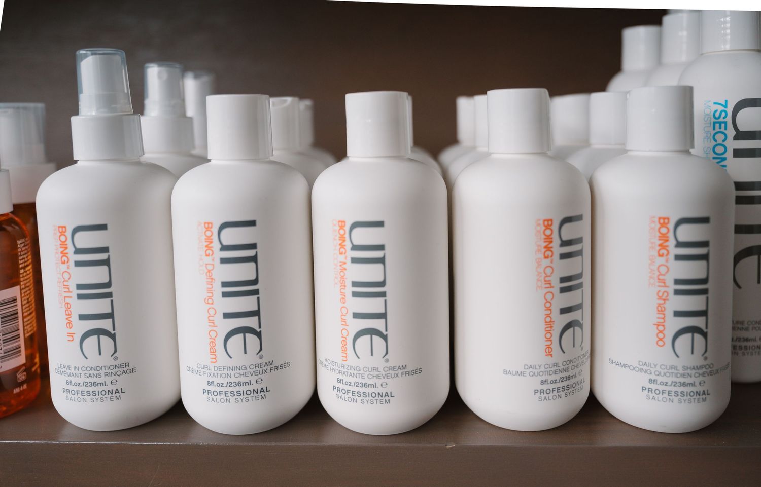 White Unite hair product bottles lined up on display shelf.