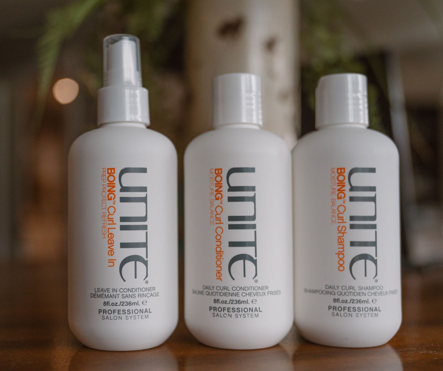 Three white Unite brand hair product bottles lined up on display.