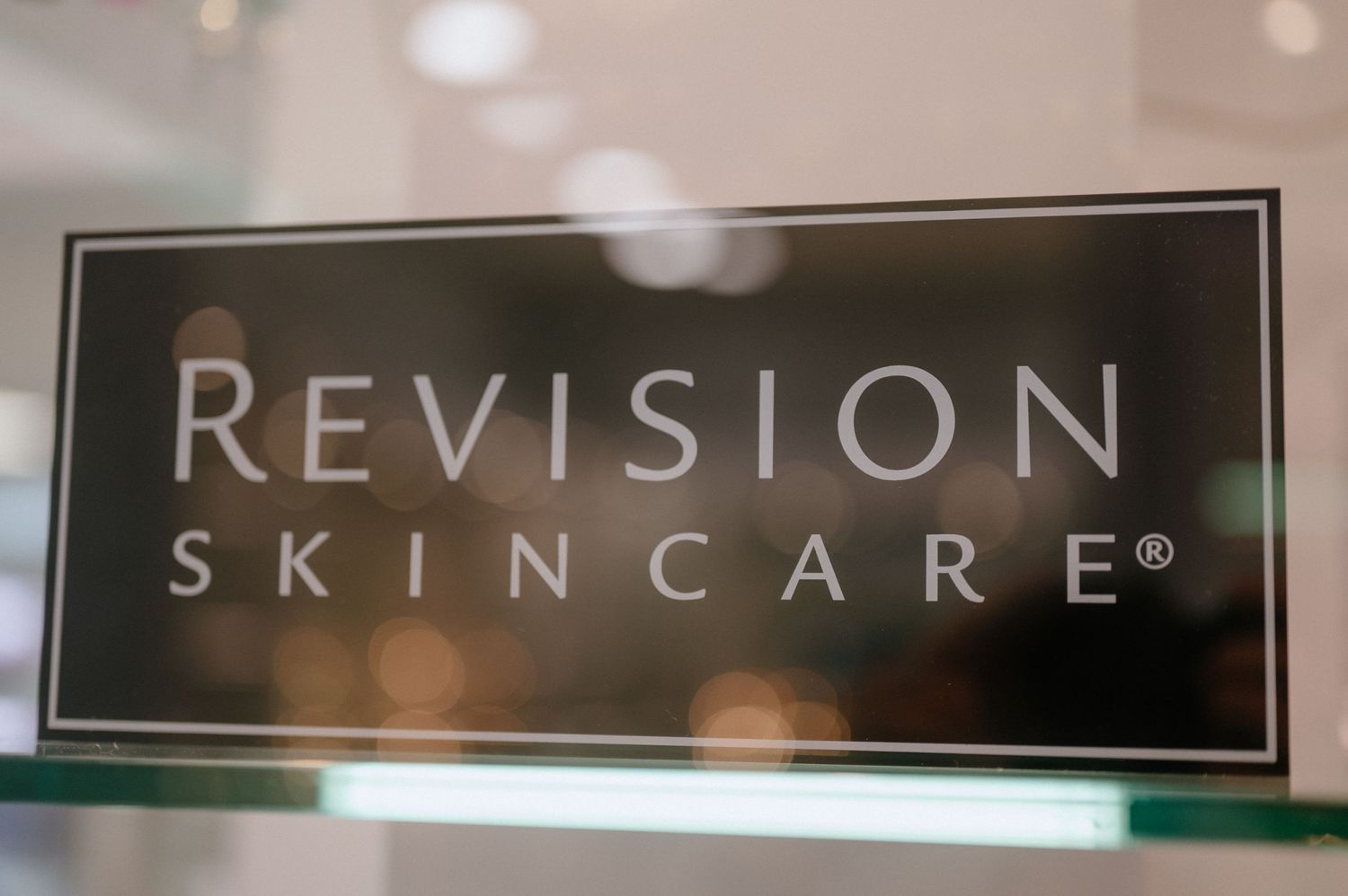 Close-up of a black Revision Skincare sign with blurred background.