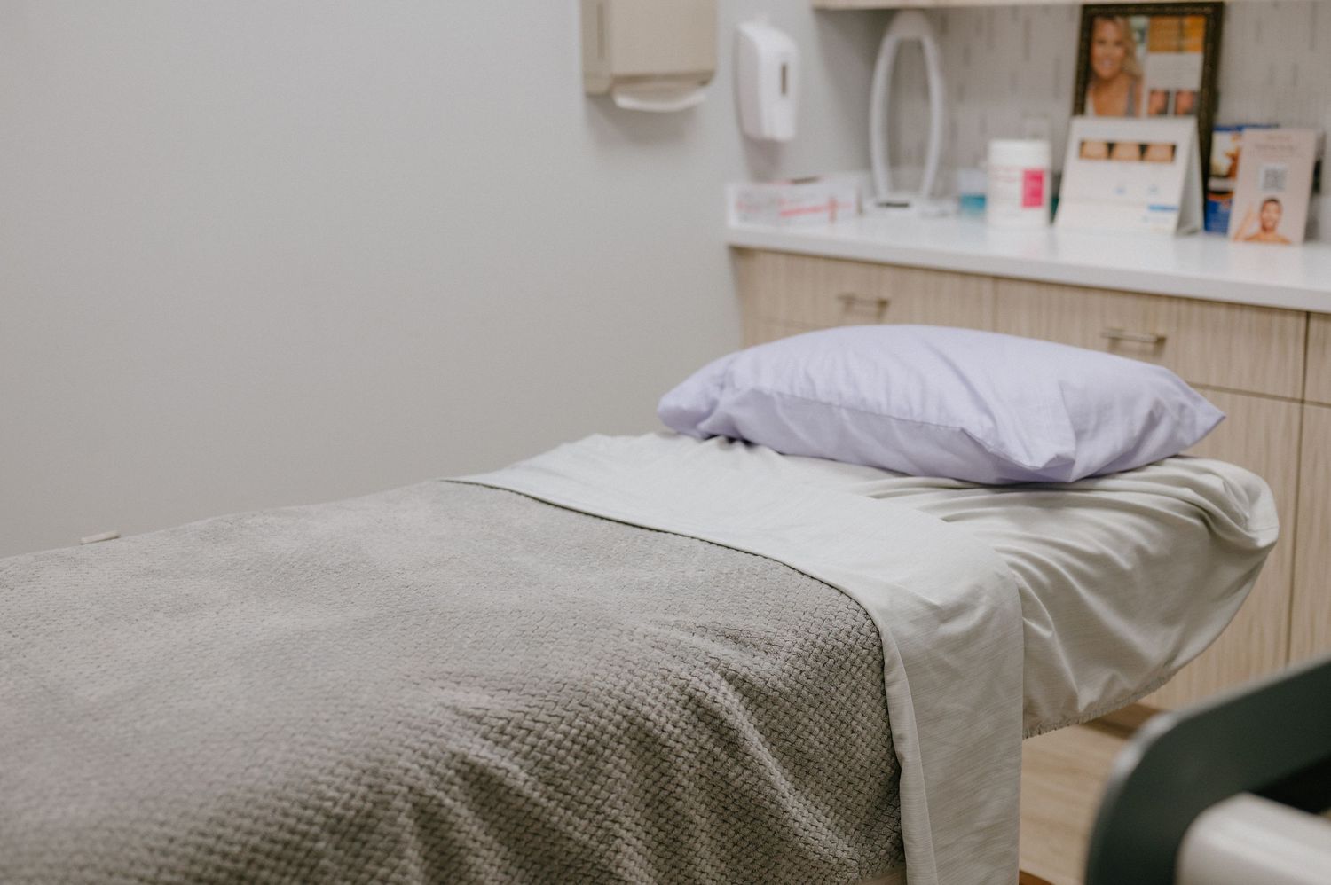 Spa treatment room with a comfortable bed covered in gray and white linens.