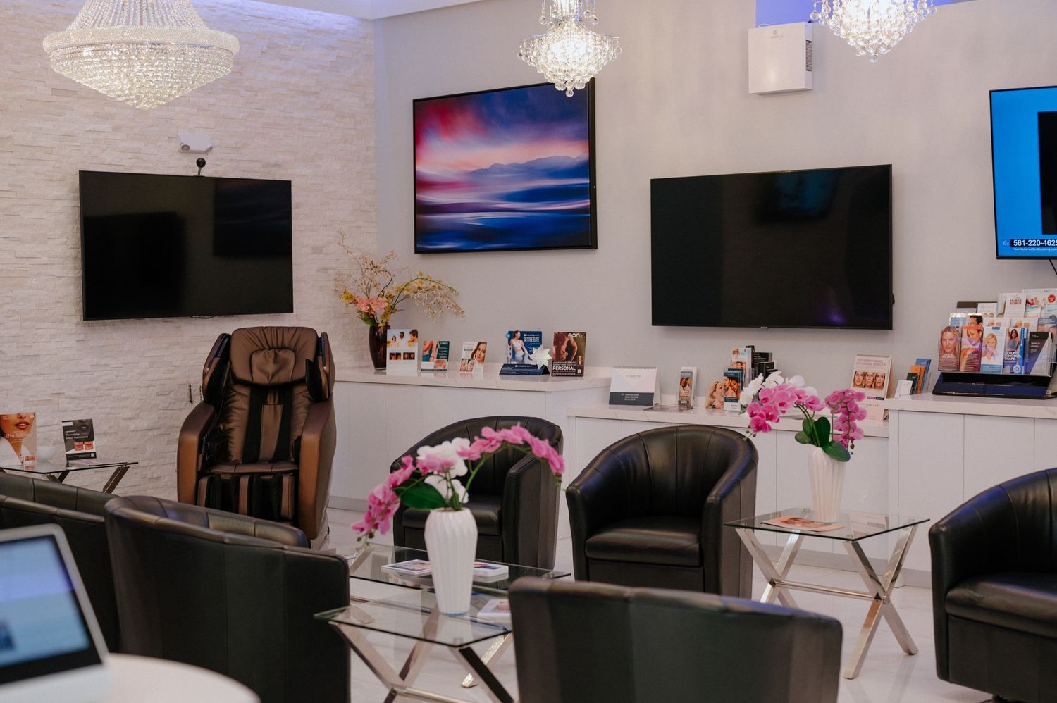 Luxury spa waiting area with massage chairs, TVs, and crystal chandeliers.