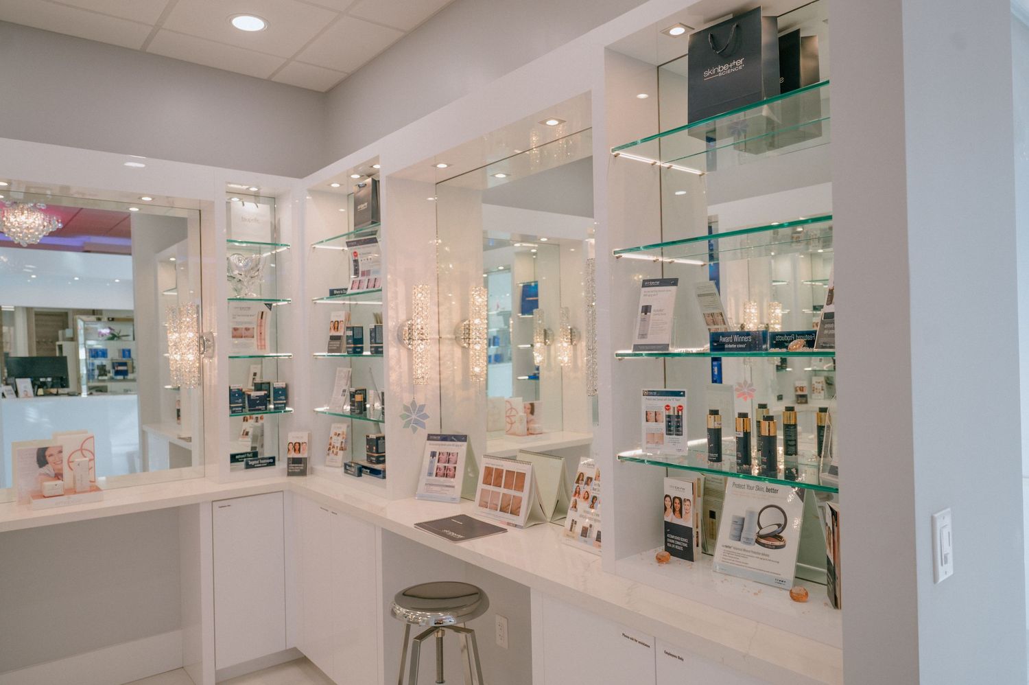 Modern medical spa retail display with white shelving and glass panels showcasing skincare products.