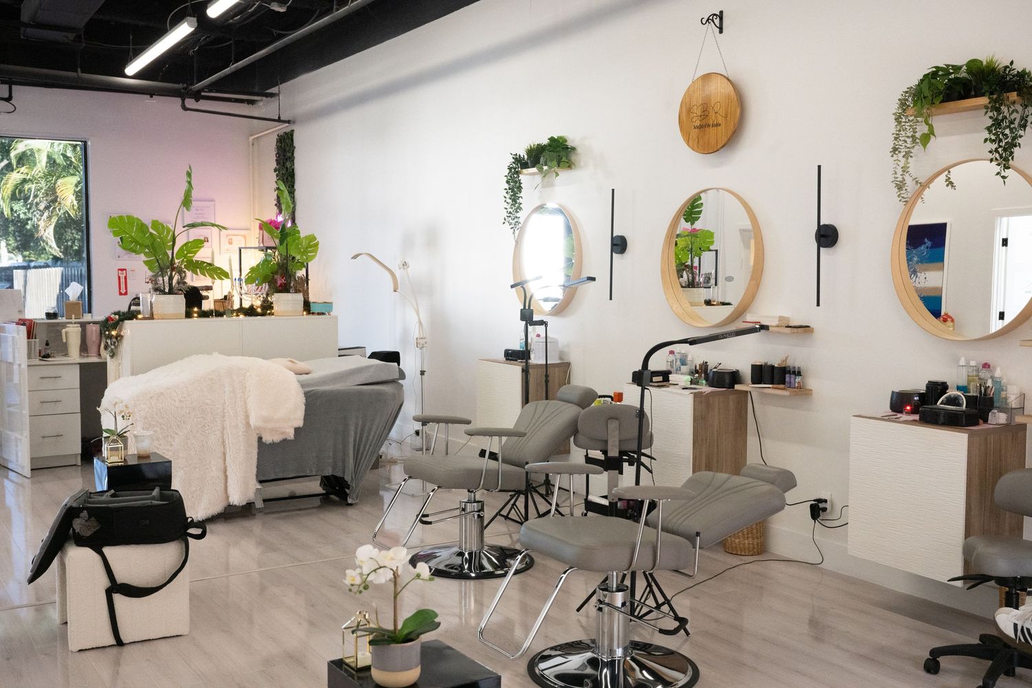 Modern beauty salon interior with white walls, mirrors, and plants.